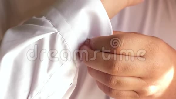 上班族早上穿衣服商人穿上白色衬衫男人在衬衫上系一个纽扣特写镜头男人视频的预览图