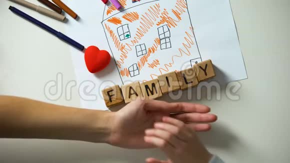 儿童牵着成人的手家庭的文字由房子图片上的立方体制成视频的预览图