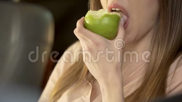 漂亮的年轻女性坐在飞机上吃着有食欲的绿苹果视频的预览图