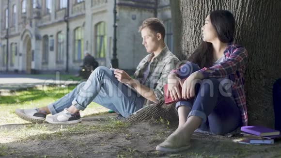 男人和女人坐在树下女孩说着什么男人看着她视频的预览图