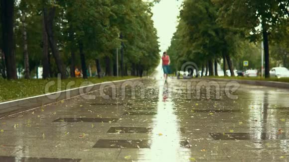 雨中一个穿着蓝色凉鞋的年轻女子走在公园的湿路旁视频的预览图