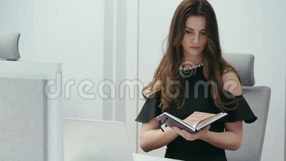 女商人坐在办公桌前拿着电脑和日历视频的预览图