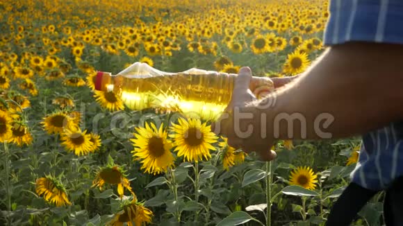 在向日葵背景下她手中的玻璃水罐中的植物油视频的预览图