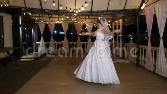 冬天的傍晚一个用灯泡装饰的露台在街上新婚夫妇正在跳他们的第一支婚礼舞视频的预览图
