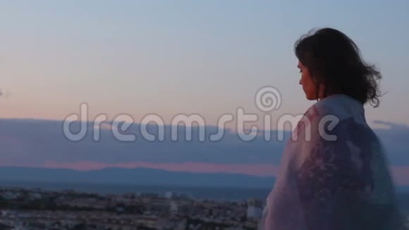 自由坚强的女人望着山脚下的城市风景风吹着她的头发视频的预览图