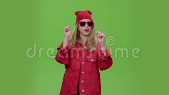 穿着时髦衣服和红色眼镜的青少年跳舞发出不同的情绪绿色屏幕视频的预览图