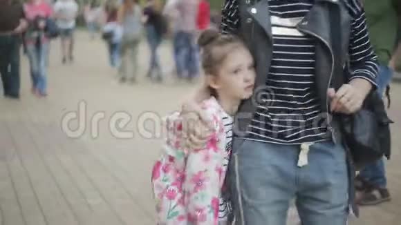 悲伤的小女孩和妈妈在拥挤的街道上散步视频的预览图