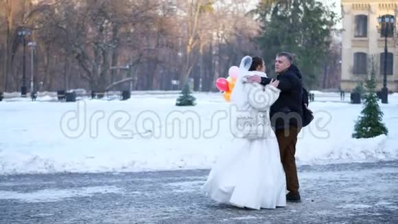 冬季婚礼新婚夫妇穿着婚纱在一个白雪皑皑的公园里与一个视频的预览图