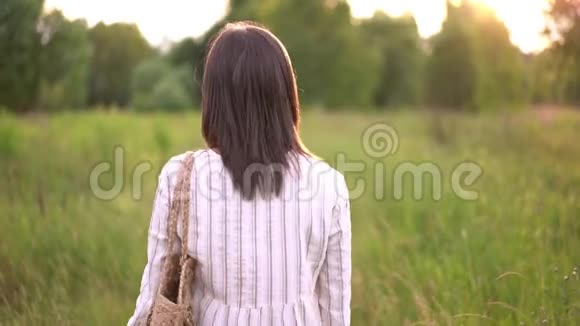 戴着牙套的女人在田野上的夕阳上微笑穿着浪漫的连衣裙飞毛头发视频的预览图