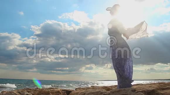 阳光下的自由女人的剪影美丽的海景躲在云层里的太阳视频的预览图