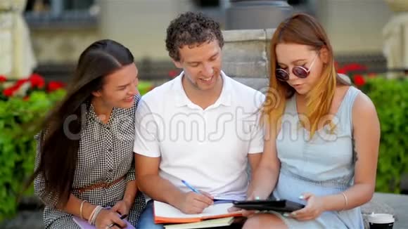 两个迷人的女孩和一个英俊的男人一起准备考试的前景坐在长凳上视频的预览图
