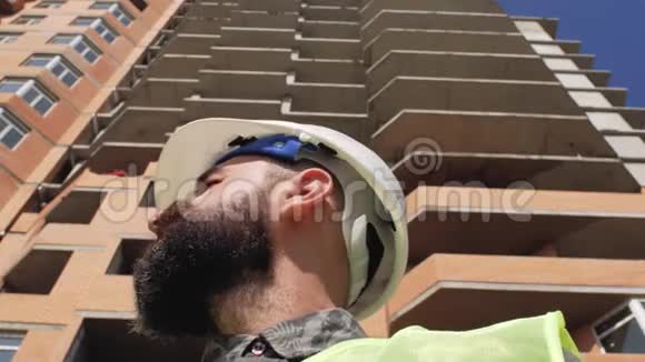 施工经理戴着安全帽留着胡子和胡子在高层建筑的背景上4k视频的预览图