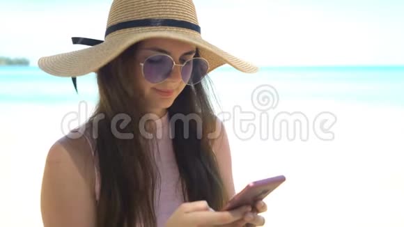 暑假在海滩上使用手机应用程序的旅行妇女视频的预览图