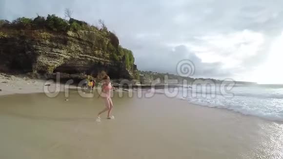 穿着泳衣的女孩在日落时分慢动作沿着海滩奔跑巴厘岛视频的预览图