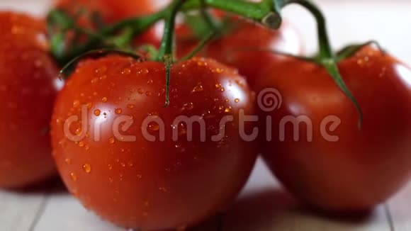 成熟的西红柿和水滴在桌子上成熟的红西红柿有绿色的茎和水滴在木头上视频的预览图