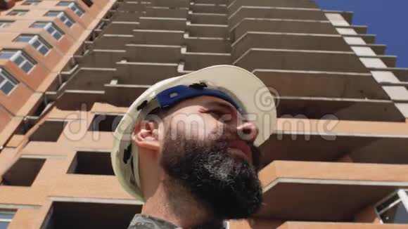 施工经理戴着安全帽留着胡子和胡子在高层建筑的背景上4k视频的预览图