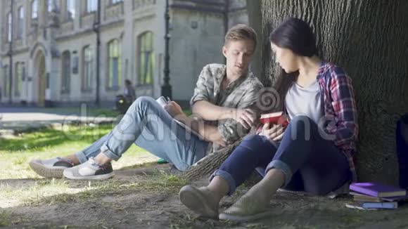 一个从女孩的头发里取出枫莎玛拉的家伙坐在靠近他的树下视频的预览图