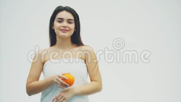 有着迷人的白种人微笑的女人的肖像在白色背景上与橙色水果隔离美容护理皮肤视频的预览图