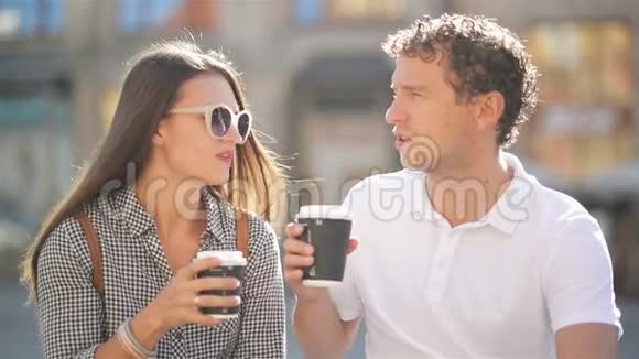 阳光明媚的夏天布鲁内特女朋友和英俊的男朋友坐在城市广场的长凳上喝咖啡视频的预览图