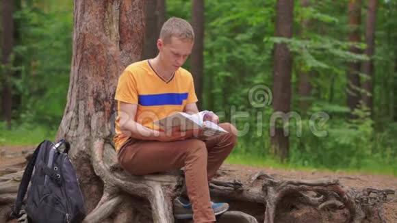 一个年轻人坐在树林里看书视频的预览图