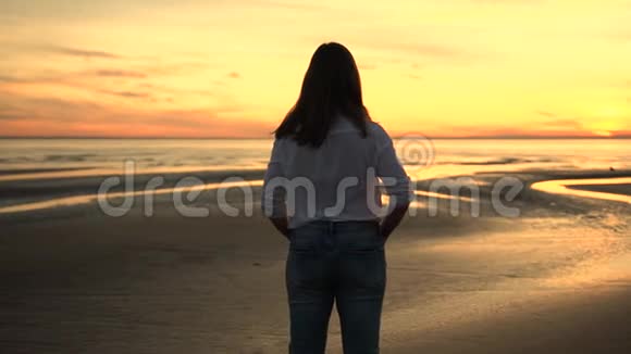 穿着白色衬衫和牛仔裤看着大海的女人视频的预览图
