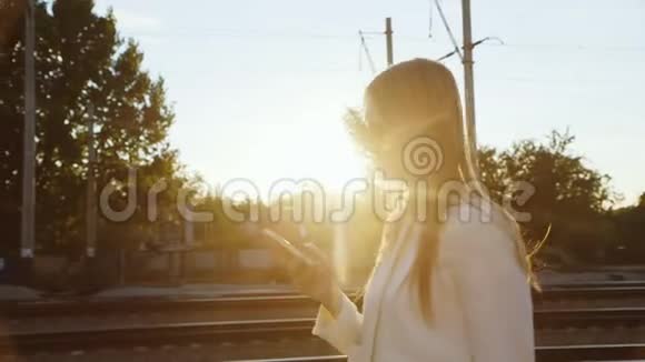 有魅力的女人走在火车站站台上用电话视频的预览图