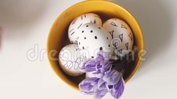 女人用复活节彩蛋在白色背景上移动黄色的杯子黄色杯子里的复活节鸡蛋黑色的白蛋视频的预览图
