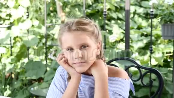 阳光孩子微笑快乐的童年概念一个漂亮的女孩坐在餐桌旁的街头咖啡馆里享受着暑假和视频的预览图