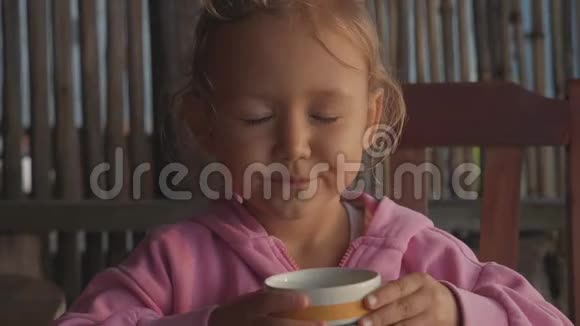 小可爱的女孩喝水看着室内摄像机慢动作视频的预览图