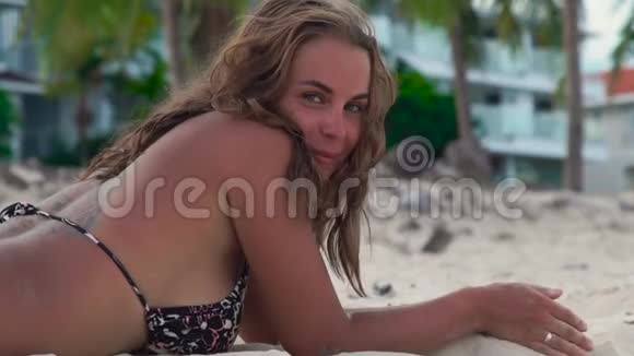 暑假期间快乐的女人在沙滩上日光浴一个微笑的女人在夏天的海滩上笑着视频的预览图