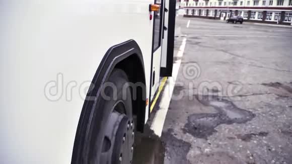 在灰色沥青背景下开始移动的带有巴士轮的白色巴士的侧面视图场景靠近白色视频的预览图
