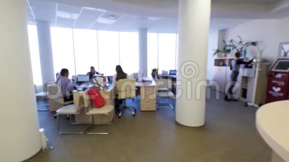 一群人在宽敞的办公室里坐在桌子旁讨论什么明亮的办公室有大窗户圆形视频的预览图