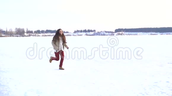 可爱的女孩留着长发在冬季的风景中奔跑视频的预览图