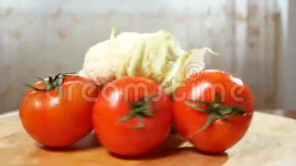 花椰菜和三个西红柿在一个木切割板上旋转4k视频的预览图