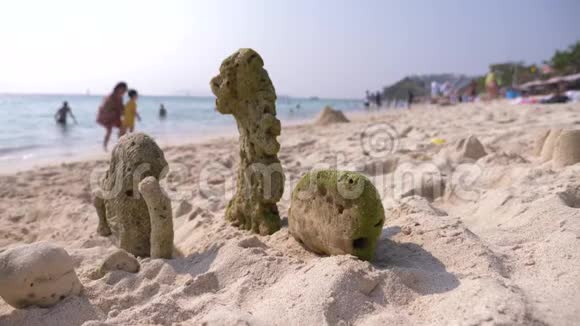 沙滩上的沙堡珊瑚被海水喷射到岸边一个面目全非的家庭在公共海滩上散步4k模糊视频的预览图