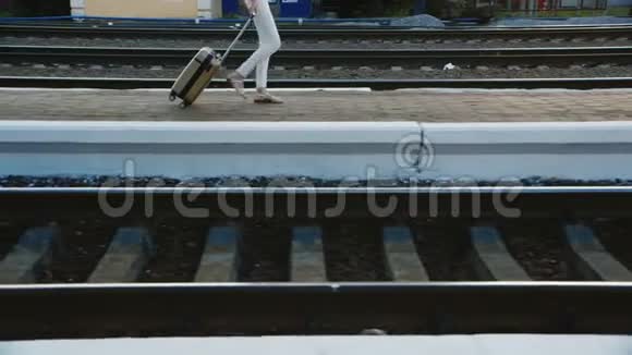 一个穿着商务服的女人穿着旅行袋在火车站在图片中只能看到腿和一个袋子视频的预览图