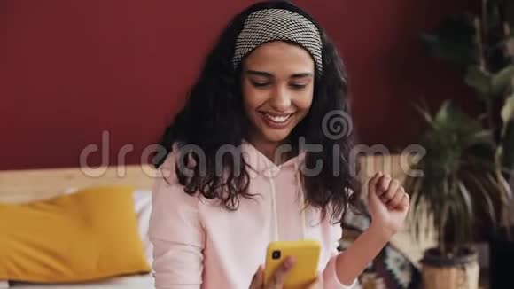年轻女子在智能手机上收到好消息美丽的非洲裔美国女孩聊天和短信智能手机视频的预览图