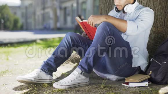 多种族男性坐在树下看书微笑着合上书快乐着视频的预览图