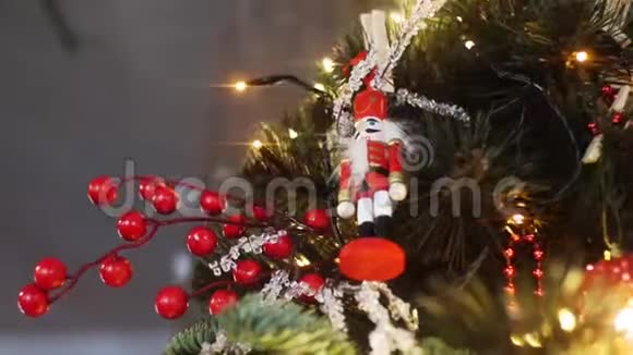 从挂在圣诞树上的红色套装的传统胡桃夹小雕像底部看灯和视频的预览图