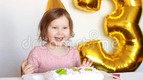 一个有趣的小女孩吃了一个美味的蛋糕这孩子在桌子上有一个甜点脸上有一张肮脏的浅色背景视频的预览图