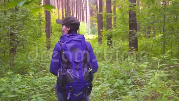 背着背包的女孩在树林里散步慢点视频的预览图