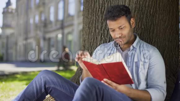 男人在树下阅读最喜欢的小说把书压在胸前做白日梦视频的预览图