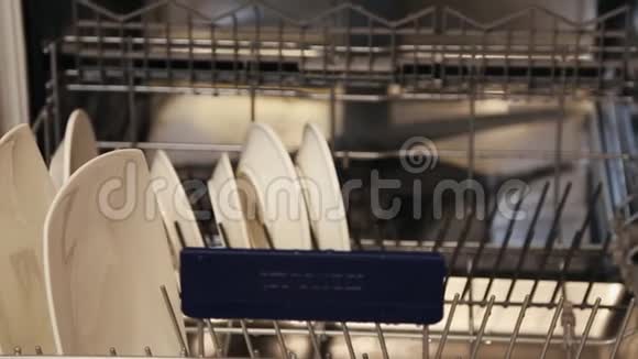 女性手在洗碗机里放大大小小的白色盘子视频的预览图