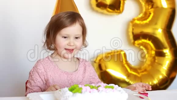 一个有趣的小女孩吃了一个美味的蛋糕一个小孩在一张浅背景的桌子上吃甜点视频的预览图