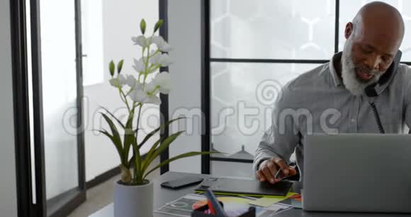 男人在座机上说话而在桌子上使用笔记本电脑视频的预览图