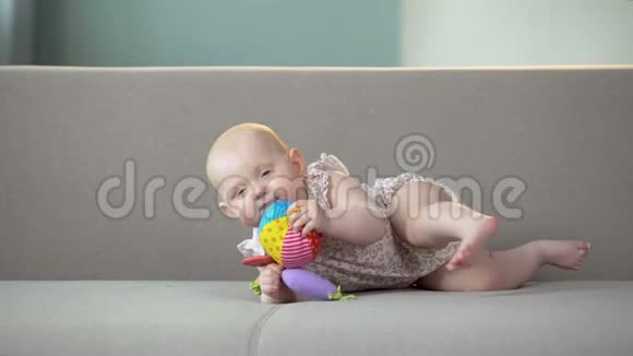 快乐女婴在沙发上玩五颜六色的玩具宝宝学爬视频的预览图