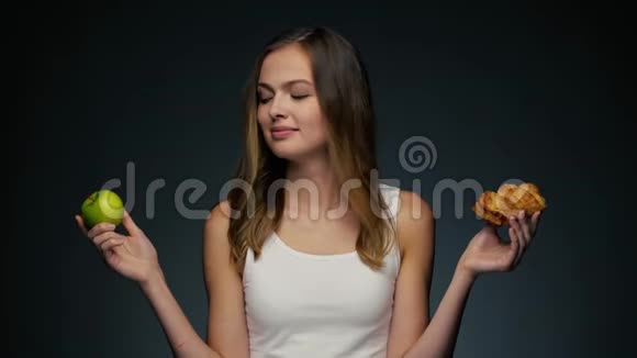 年轻美丽的高加索女人与苹果的肖像选择垃圾食品视频的预览图