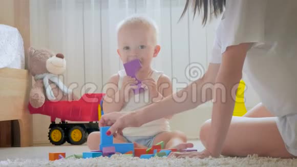 妈妈和她的孩子在室内玩玩具在家里在地板上爬行有趣的小男孩妈妈和小儿子一起玩视频的预览图