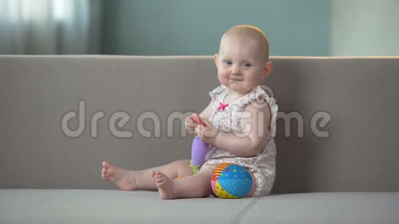 婴儿微笑着在沙发上玩玩具婴儿在尿布上享受舒适视频的预览图