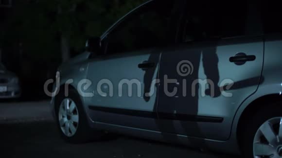 强盗剪影手持蝙蝠等待夜间停车犯罪活动视频的预览图